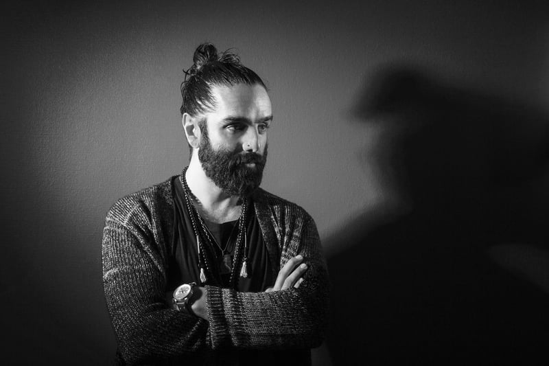 Svartvitt porträtt av Navid Modiri med armarna i kors